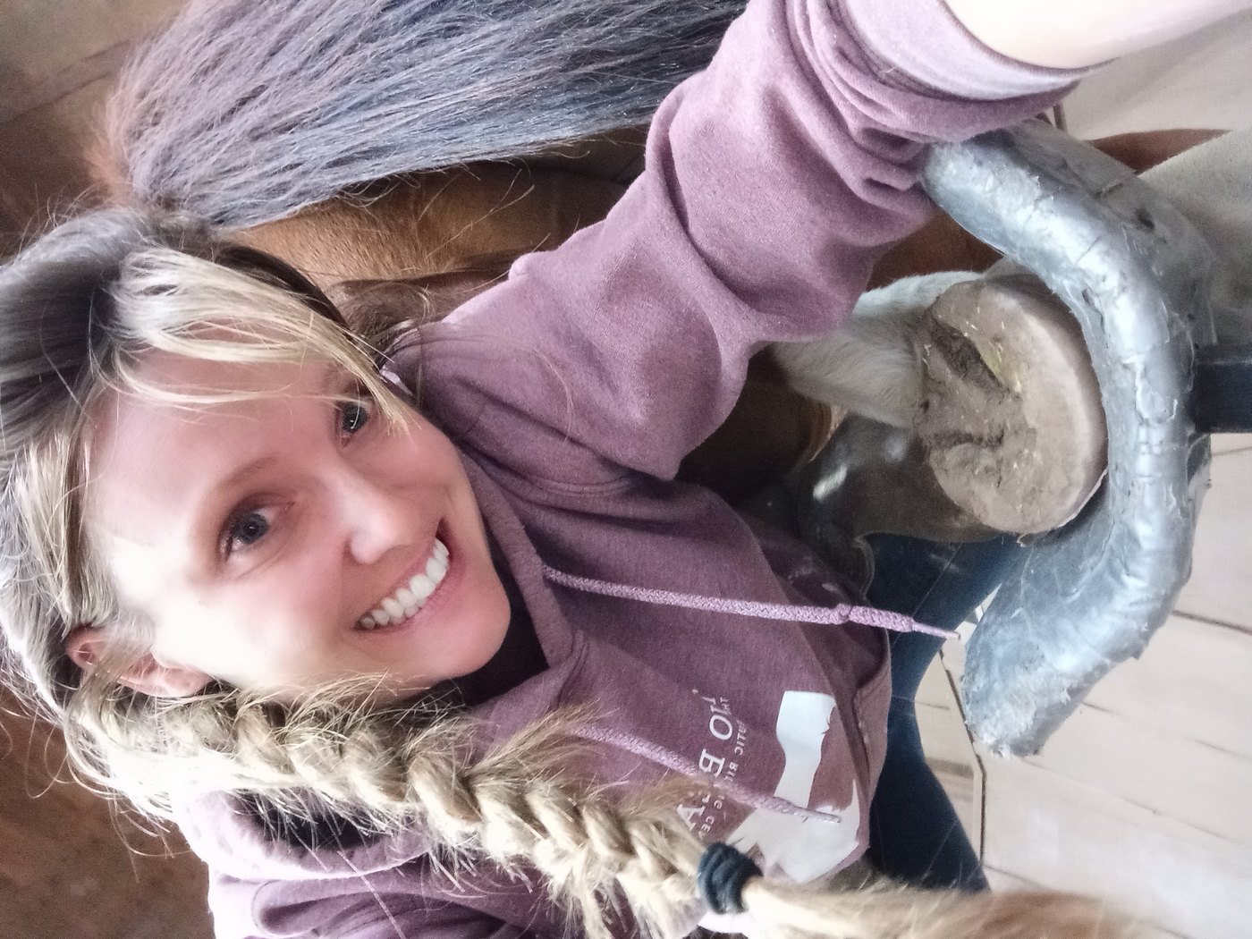 Kat holding a horse's foot on a hoof stand during a trim