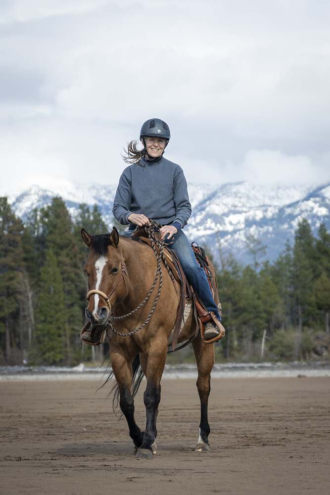 Kat's mother riding her buckskin up the beach with snow still on the mountains behind her