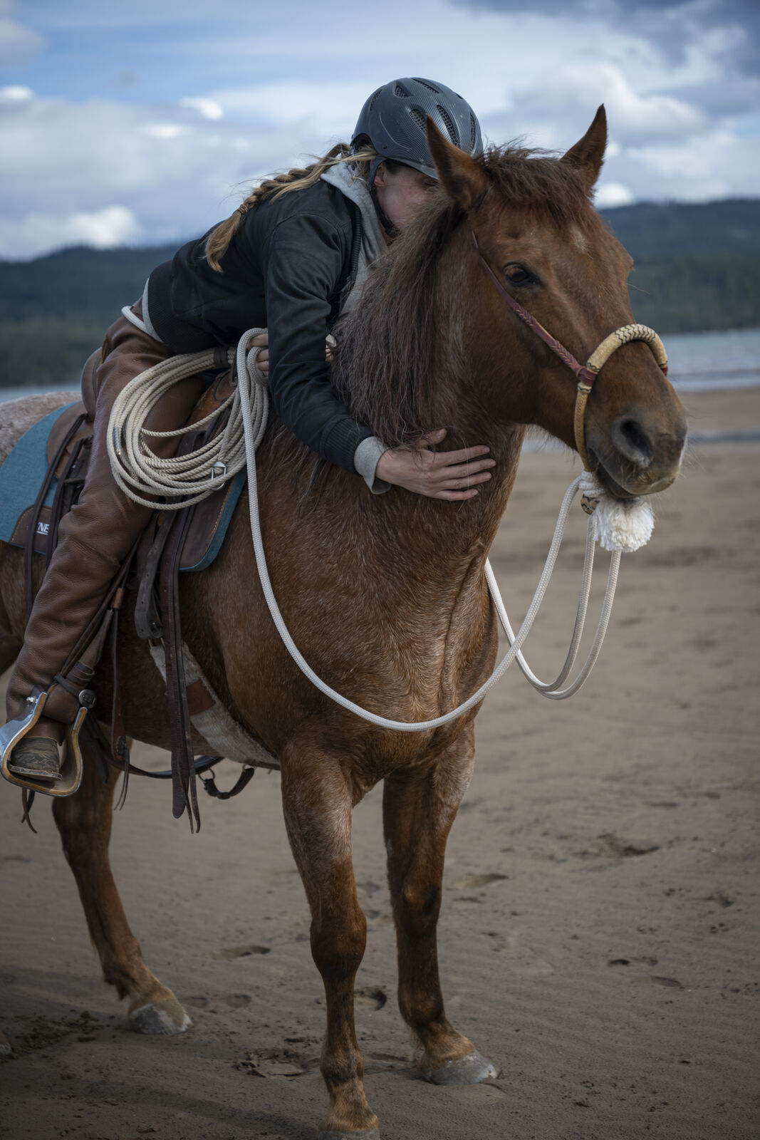 Kat leaning forward in the saddle with both arms around her horse&rsquo;s neck